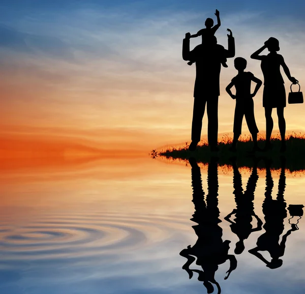 夕焼け空に家族のシルエット。水 — ストック写真