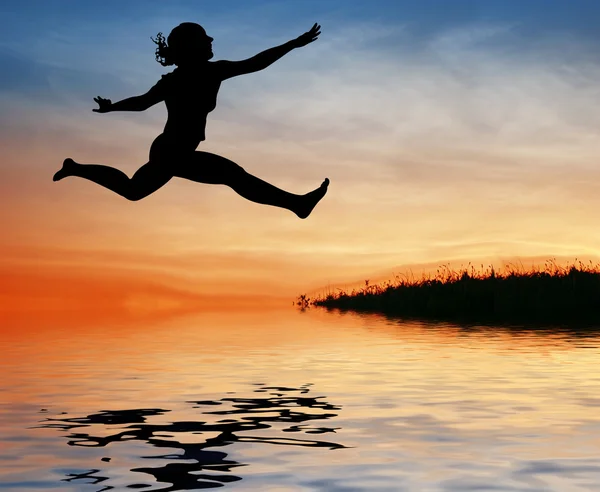 Siluett hoppa flicka på vatten — Stockfoto