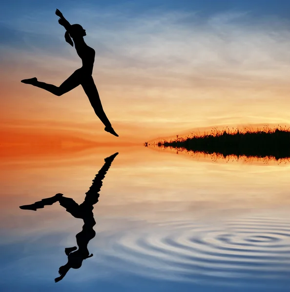 Silueta skok dívka na vodě — Stock fotografie