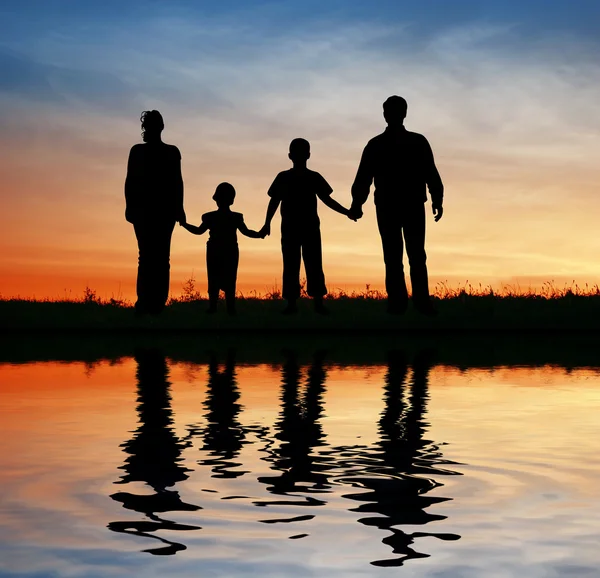 Family of four on sunset sky, water — Stock Photo, Image