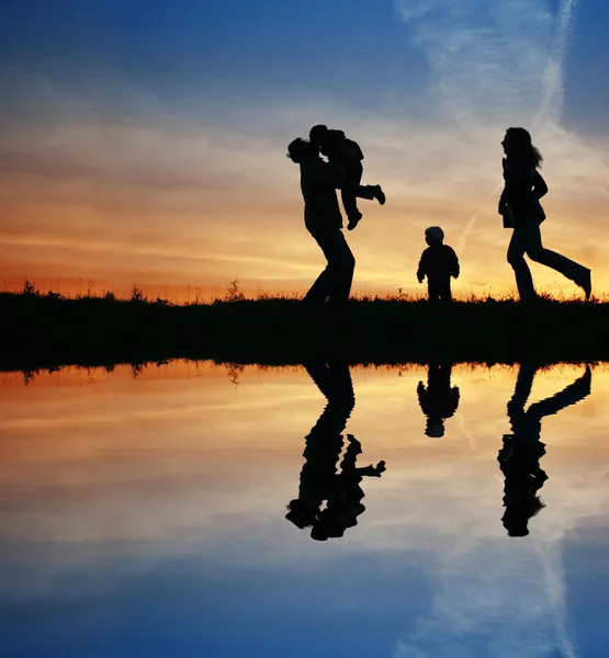 Silhouet familie van vier en water — Stockfoto