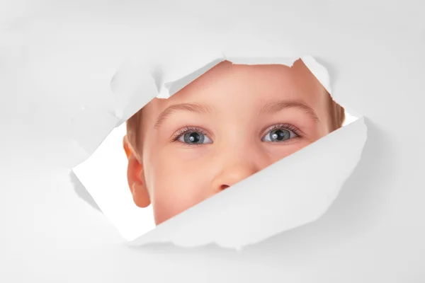 Child looks in a hole in a sheet of a paper — Stock Photo, Image