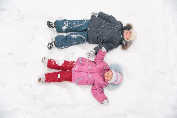 Двое детей лежат на снегу — стоковое фото