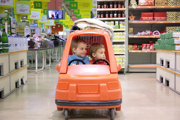 Дети в игрушечном автомобиле в супермаркете — стоковое фото