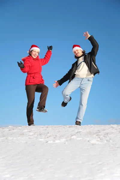 Casal dança na colina de neve em chapéus de santa claus — Fotografia de Stock