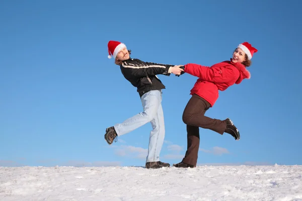 Taneční pár na kopci sněhu v santa claus klobouky 2 — Stock fotografie
