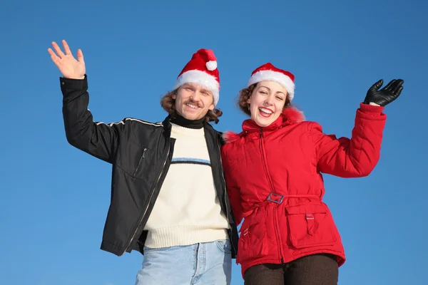 Пара на фоне голубого неба зимой в шляпах Санта-Клауса — стоковое фото