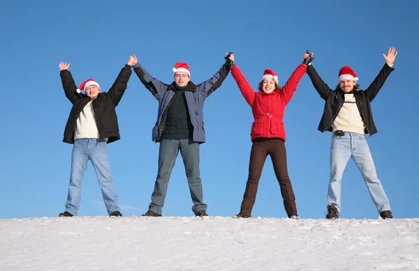 Čtyři pozdravy přátel na sníh v santa claus klobouky — Stock fotografie