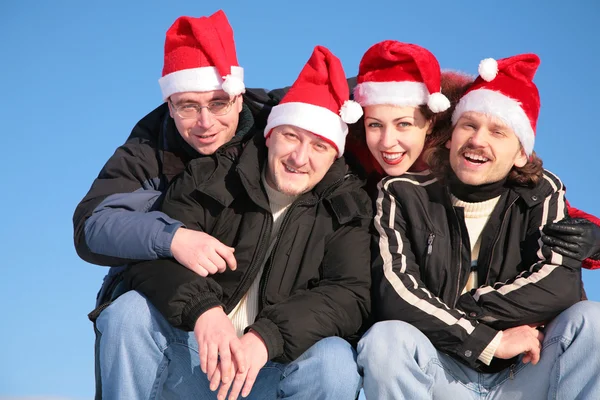 サンタ クロースの帽子で青い空を背景に 4 人の友人 — ストック写真