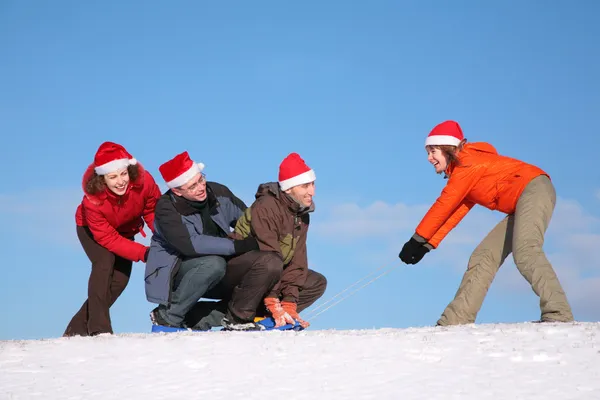 One woman pull two men on sled, other woman push them — Stock Photo, Image