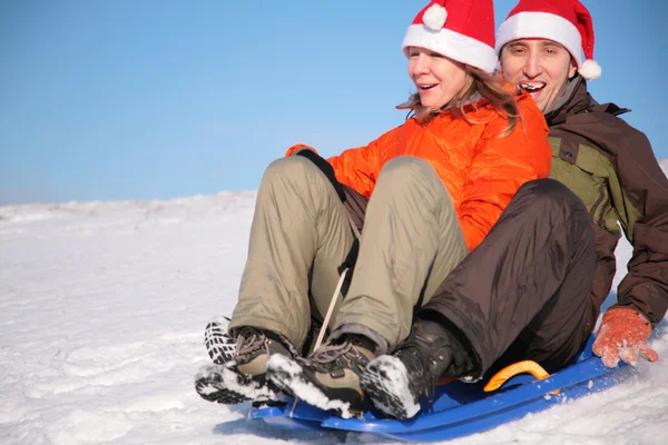 男人和女人在圣诞老人帽子坐在雪橇上 — 图库照片