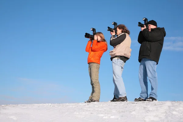 Три фотографа на снежном холме — стоковое фото
