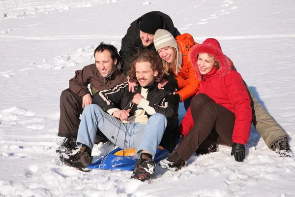 Five friends with plastic sled sit on snow — Stock Photo, Image