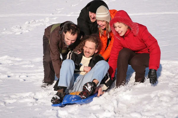 Group of friends push another one on plastic sled — Stock Photo, Image