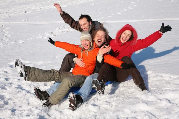 Group of friends sit on plastic sled on snow 2 — Stock Photo, Image