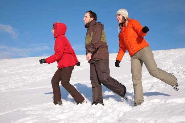 Three friends walk on snow on hillside — Stock Photo, Image