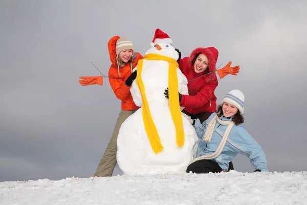 Three young women and snowman 2 — Stock Photo, Image