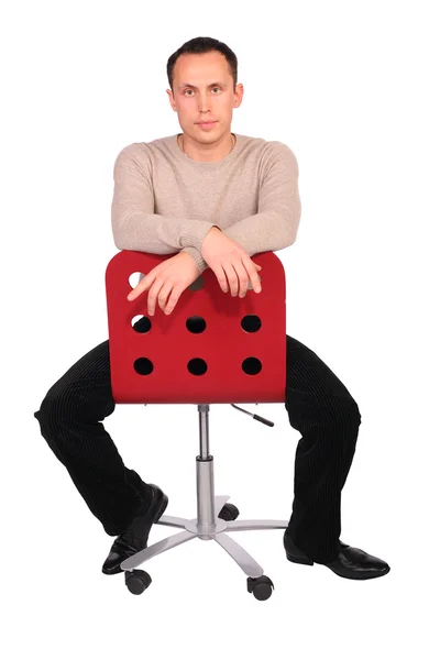 Genç adam kırmızı koltuğa oturur — Stok fotoğraf