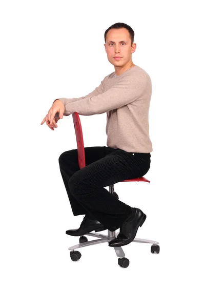 Young man sits on red chair sideview — Stock Photo, Image