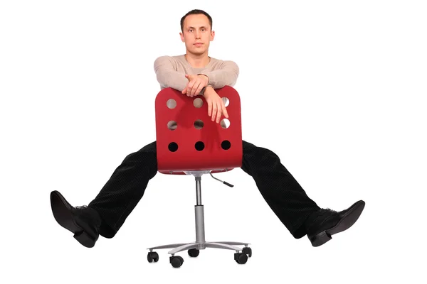 Молодий чоловік сидить на червоному стільці розтягнуті ноги — стокове фото