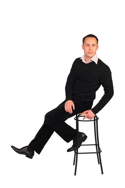 Jeune homme en noir assis sur un tabouret — Photo