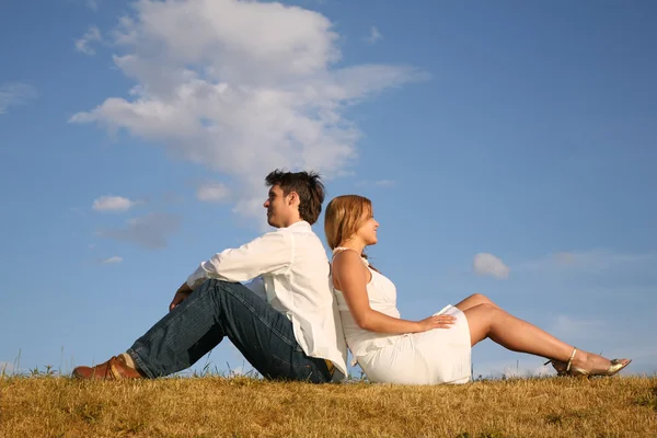Couple sit on meadow back to back — Stock Photo, Image