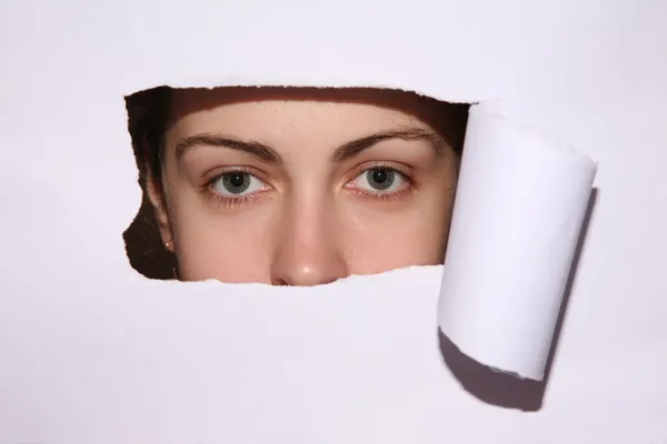 Woman looks in the hole of the sheet of paper — Stock Photo, Image
