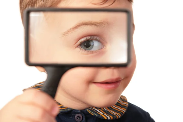 Bambino sorridente guarda attraverso lente di ingrandimento — Foto Stock