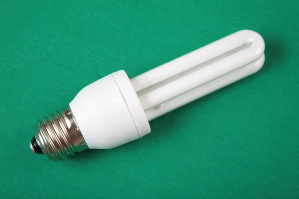 Lampe à économie d'énergie sur fond vert — Photo