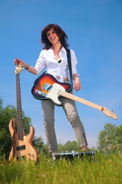 Женщина с двумя гитарами на траве — стоковое фото