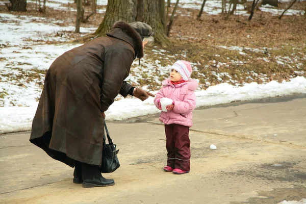 Little girl with snowball speaks with woman — Stock Photo, Image