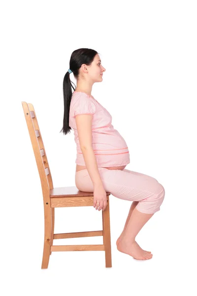 Menina grávida senta-se na vista lateral da cadeira — Fotografia de Stock