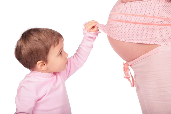 Маленькая девочка и беременная посмотрите в — стоковое фото