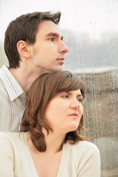 Menino com a menina contra o fundo da janela molhada — Fotografia de Stock