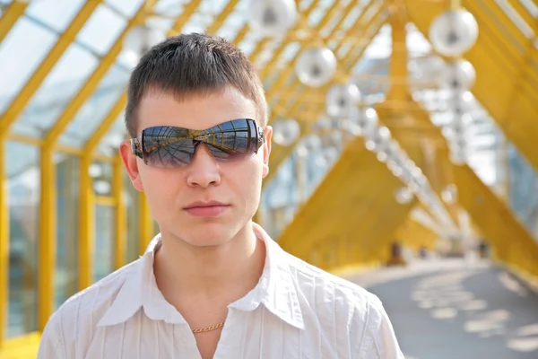 Jeune homme en lunettes de soleil sur passerelle — Photo