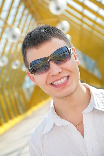 Jovem sorridente homem em óculos de sol na passarela — Fotografia de Stock