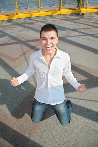 Junger Mann steht auf Knien auf der Fußgängerbrücke — Stockfoto