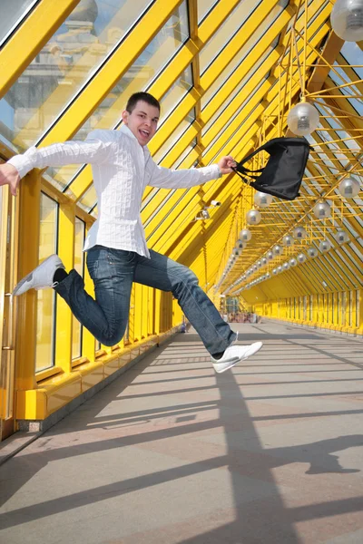 Young man jumps with bag on footbridge — Stock Photo, Image