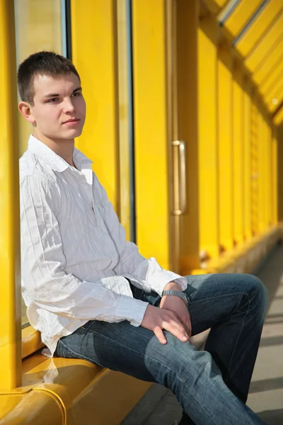 Mladý muž sedí na lávce — Stock fotografie