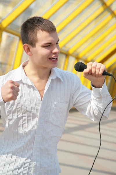 Молодой человек с микрофоном на пешеходном мосту — стоковое фото