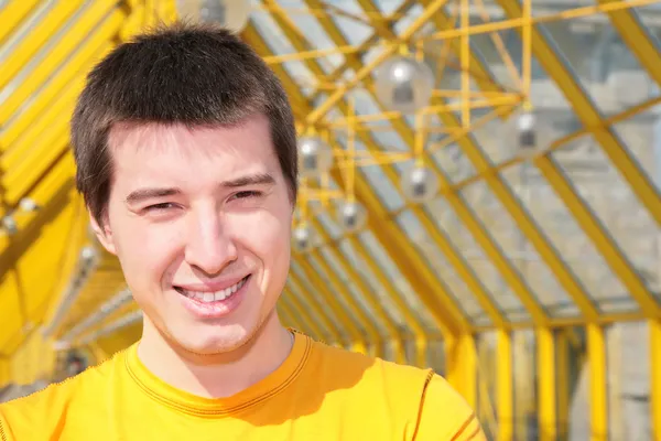 Junger lächelnder Mann im gelben Hemd auf Fußgängerbrücke — Stockfoto