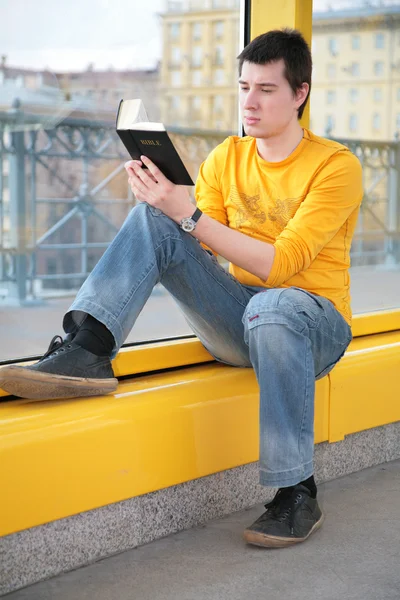 Ásia menino senta no footbridge e lê bíblia — Fotografia de Stock