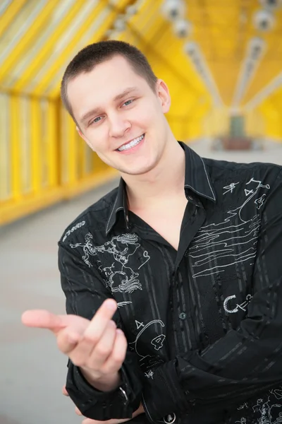 Młody chłopak uśmiechający się w czarną koszulę czyni gest — Zdjęcie stockowe