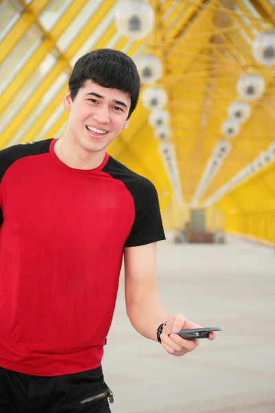 Sarı yaya köprüsü üzerinde cep telefonu ile genç adam — Stok fotoğraf