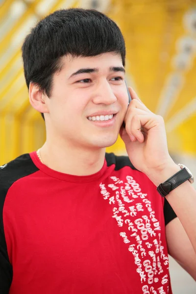 Jonge man gesprekken door cell phone on gele Footbridge based — Stockfoto