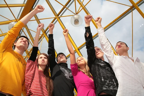 Group of friends stands with raised fists on footbridge — Stock Photo, Image