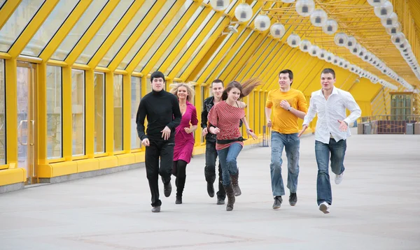 Skupina mladých přátel běží na žluté lávka — Stock fotografie