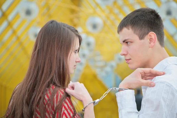 Young couple with handcuffs on footbridge — Stock Photo, Image