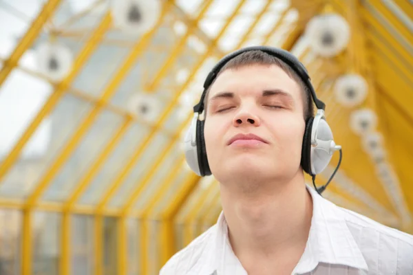 Young man listens music on footbridge — Stock Photo, Image