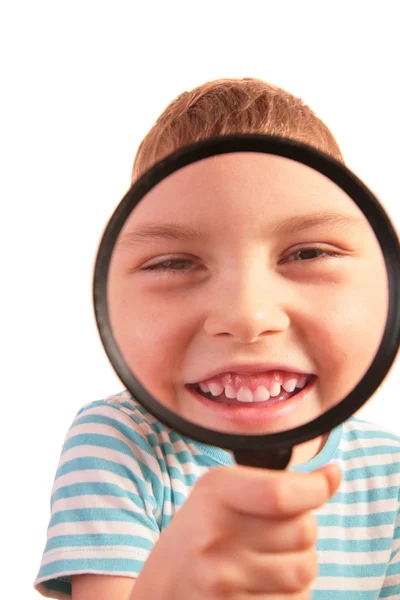 Smiling child looks through magnifier — Stock Photo, Image